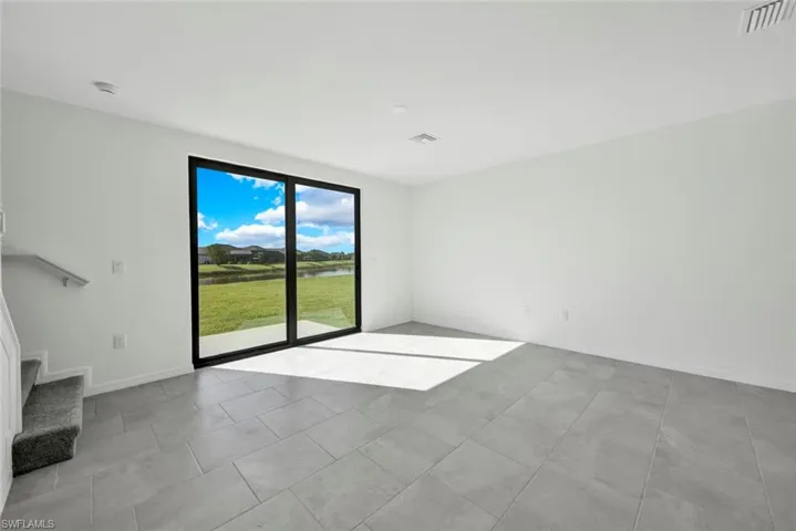 Unfurnished room featuring a water view, stairs, a smoke detector, and baseboards