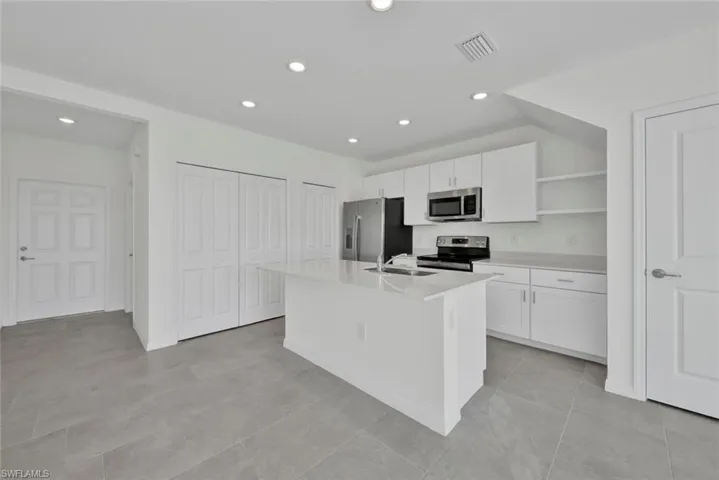 Kitchen with appliances with stainless steel finishes, open shelves, white cabinets, a sink, and recessed lighting