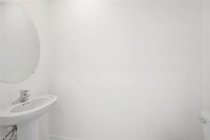 Half bath with baseboards, toilet, and a sink