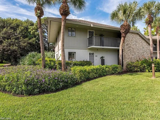 Back of house with a balcony, a yard, and stucco siding