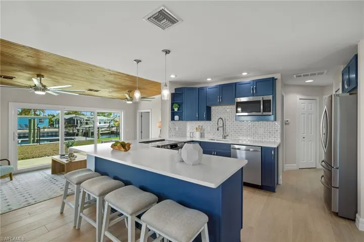 Kitchen featuring a kitchen breakfast bar, light hardwood / wood-style flooring, decorative light fixtures, kitchen peninsula, and stainless steel appliances