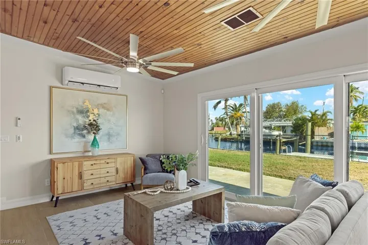 Sitting room featuring a wall mounted air conditioner, a water view, light hardwood / wood-style flooring, and a healthy amount of sunlight