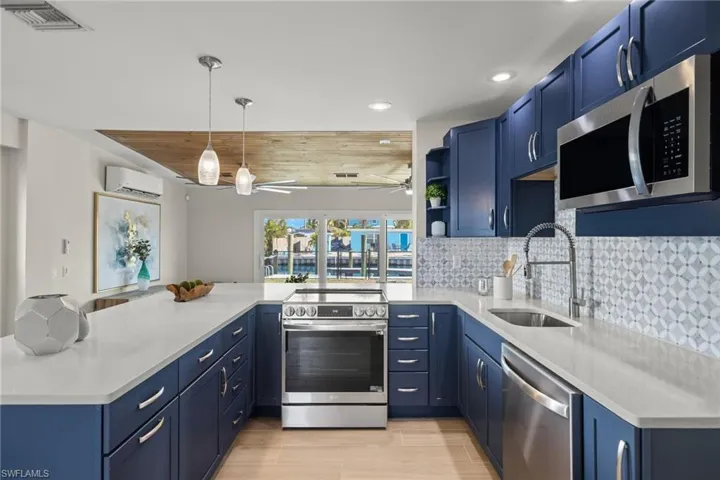 Kitchen featuring sink, stainless steel appliances, an AC wall unit, kitchen peninsula, and decorative light fixtures