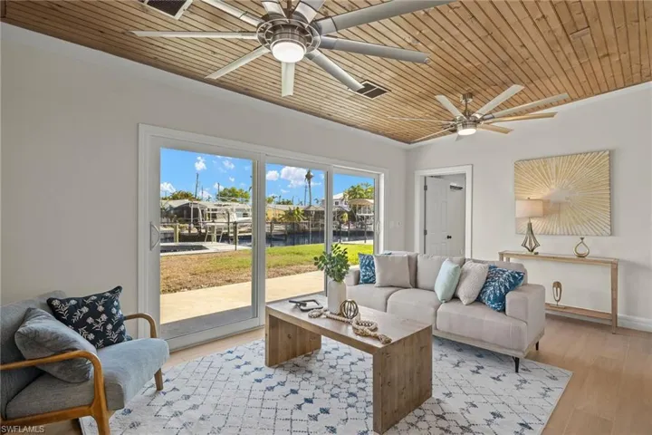 Living room with light wood-type flooring, crown molding, ceiling fan, and wooden ceiling