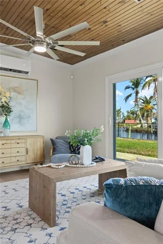 Living area featuring light hardwood / wood-style flooring, a water view, wood ceiling, and a wall mounted air conditioner