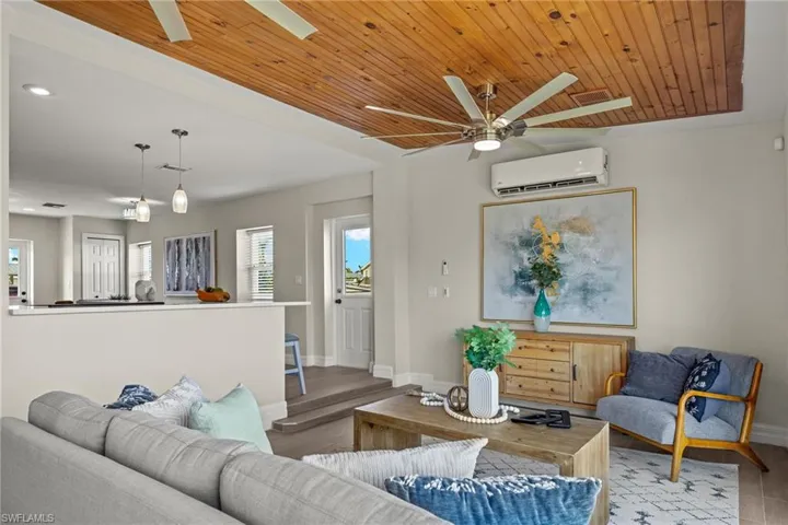 Living room with wood ceiling, ceiling fan, light hardwood / wood-style floors, and a wall mounted air conditioner