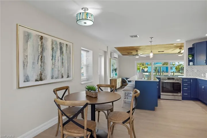 Dining space with light hardwood / wood-style floors, an AC wall unit, and a healthy amount of sunlight