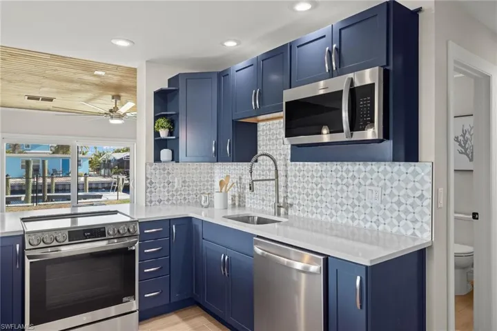 Kitchen with blue cabinetry, stainless steel appliances, and sink