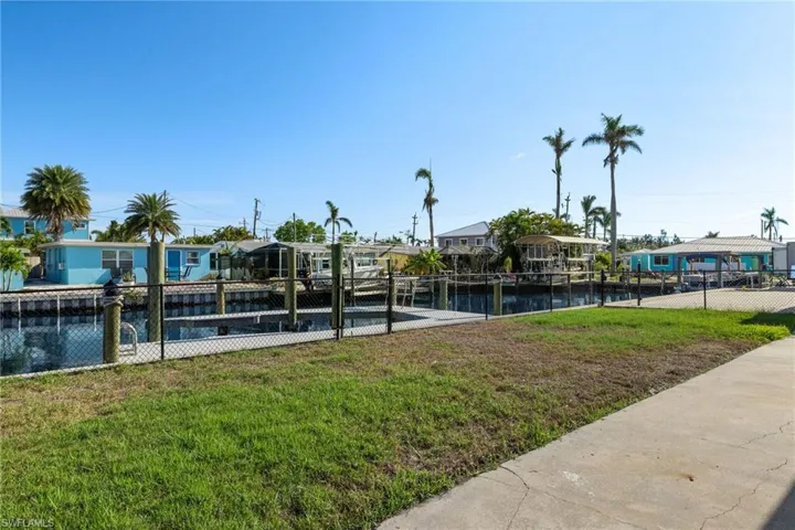 View of home's community featuring a water view, a dock, and a lawn