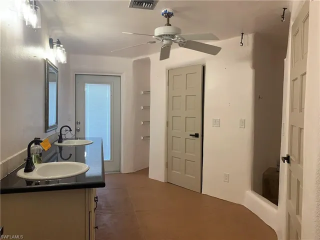 Pool Bathroom with double vanity, double toilet stalls, visible vents, and a ceiling fan