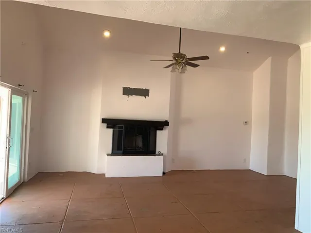 Living room featuring recessed lighting, a glass covered fireplace, ceiling fan, high vaulted ceiling, and tile patterned floors