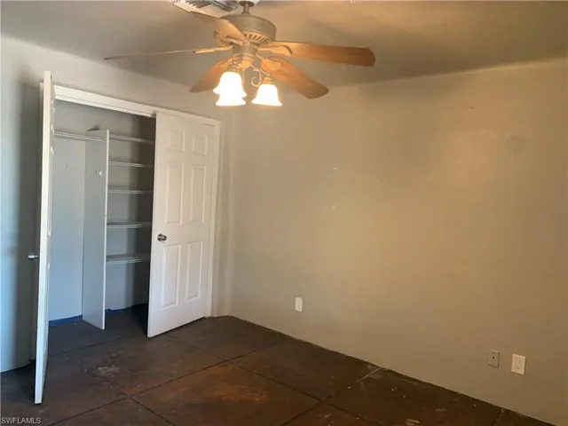 Unfurnished bedroom with ceiling fan and a closet