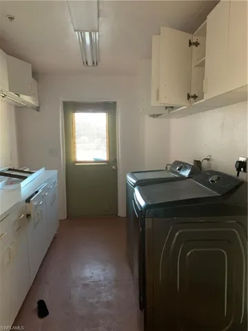 Clothes washing area featuring cabinet space and washer and clothes dryer