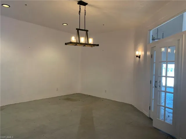Empty room with concrete floors and an inviting chandelier
