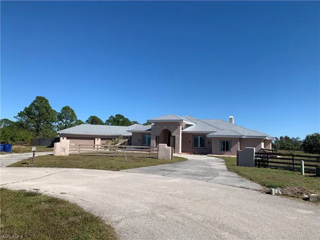 View of front of home featuring metal roof, fence, stucco siding, a standing seam roof, and a front yard