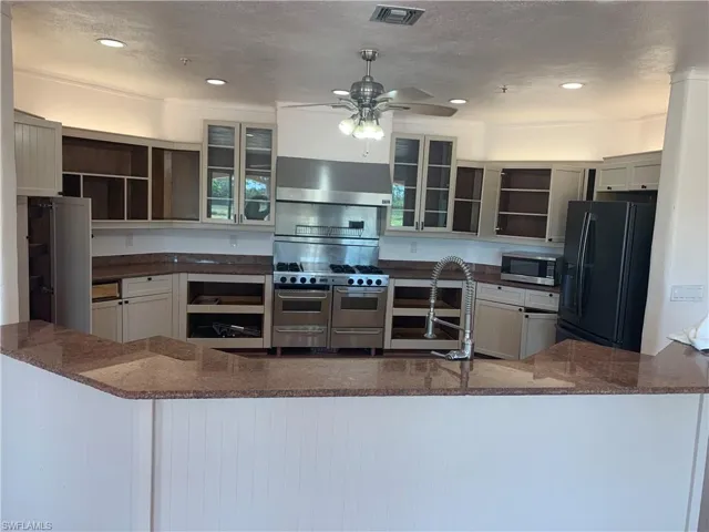 Kitchen featuring visible vents, appliances with stainless steel finishes, extractor fan, a textured ceiling, and open shelves