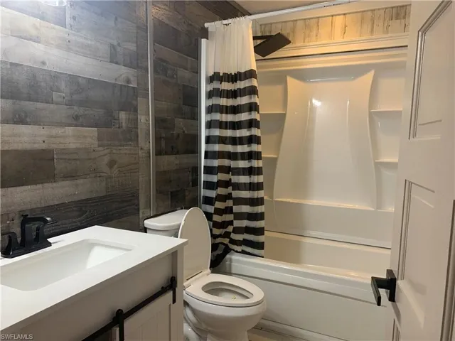 Full bath featuring shower / bathtub combination with curtain, toilet, and vanity