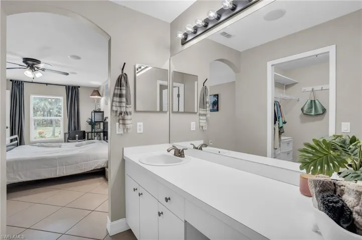 Bathroom featuring tile floors, ceiling fan, and vanity with extensive cabinet space