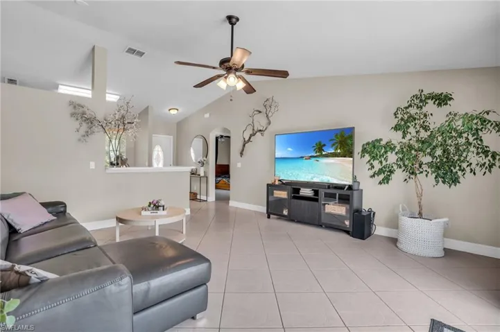 Tiled living room featuring ceiling fan and lofted ceiling