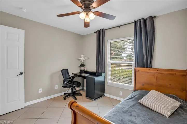 Bedroom with multiple windows, light tile floors, and ceiling fan