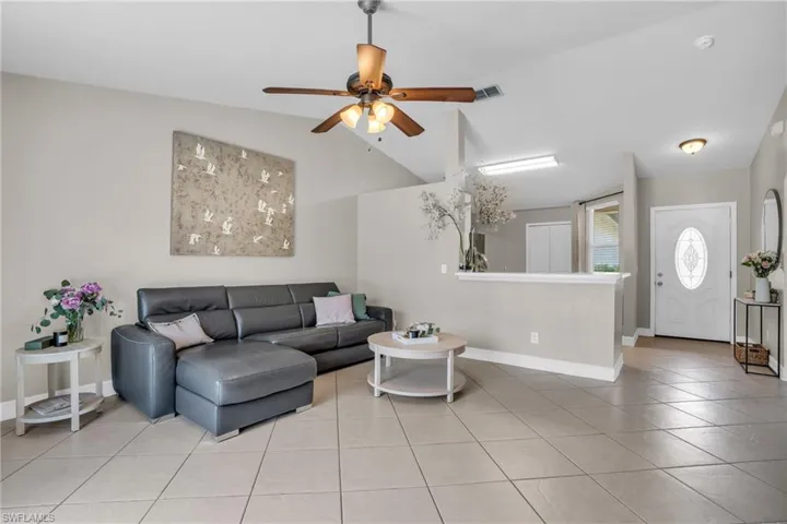 Tiled living room featuring ceiling fan and vaulted ceiling