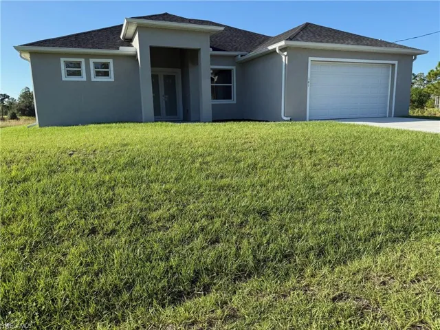 View of front of home featuring stucco siding, a front lawn, driveway, a garage, and roof with shingles