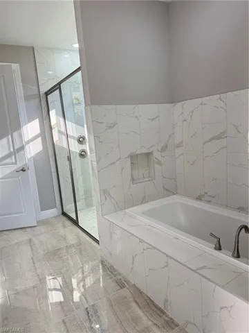 Bathroom with a marble finish shower and a bath