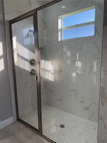 Full bathroom with a marble finish shower and baseboards