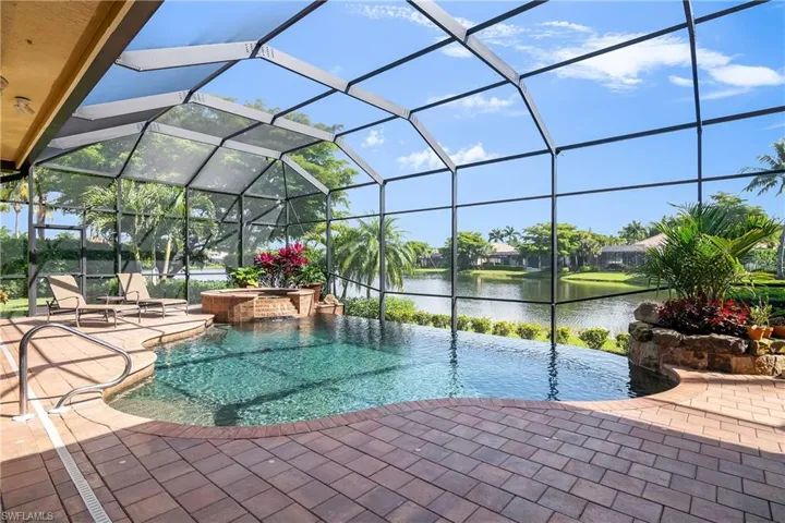 Lanai with saltwater vanishing edge pool and spa, water view from left and right. Note small white inserts on deck for safety net "fence" in case of visiting young children. Net is provided.