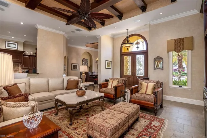 Front door with double leaded glass arched entry, kitchen to left and dining room to right. Neutral ceramic tile floor.