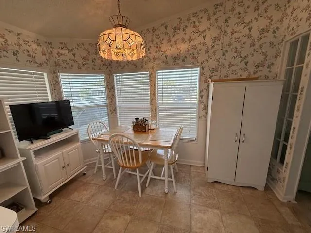 Dining space with baseboards, wallpapered walls, ornamental molding, and a textured ceiling