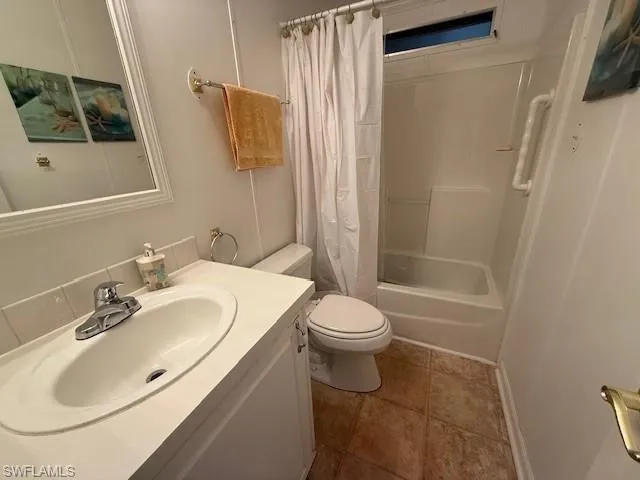 Full bathroom with shower / bathtub combination with curtain, toilet, tile patterned flooring, and vanity