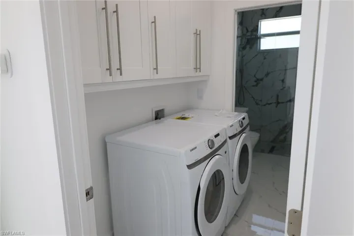 Laundry room with light marble finish flooring and washer and clothes dryer