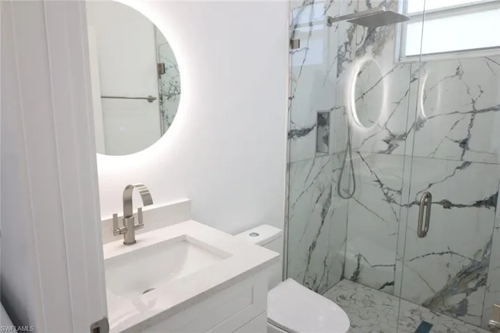 Full bath featuring vanity and a marble finish shower