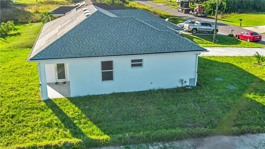 View of home's exterior featuring a lawn, a shingled roof, and stucco siding