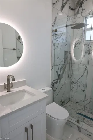 Full bathroom with vanity, a marble finish shower, and marble look tiles