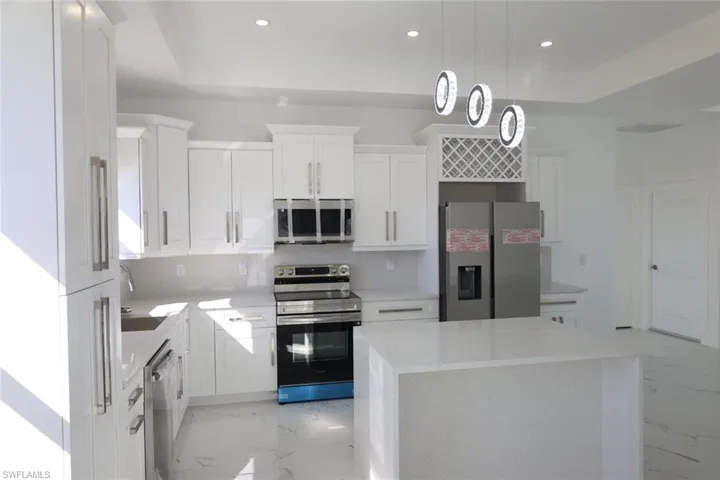 Kitchen with stainless steel appliances, light marble finish floors, light stone countertops, and recessed lighting