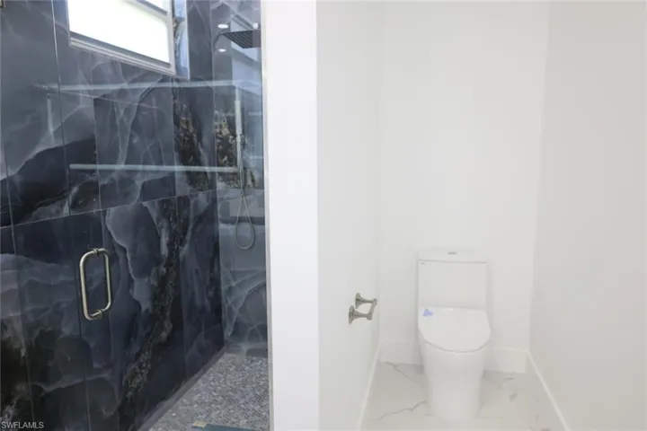 Bathroom featuring a marble finish shower and marble look tile flooring