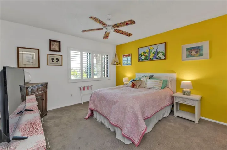 Carpeted bedroom featuring ceiling fan and baseboards