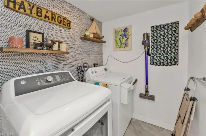 Clothes washing area with baseboards, laundry area, an accent wall, and washer and dryer