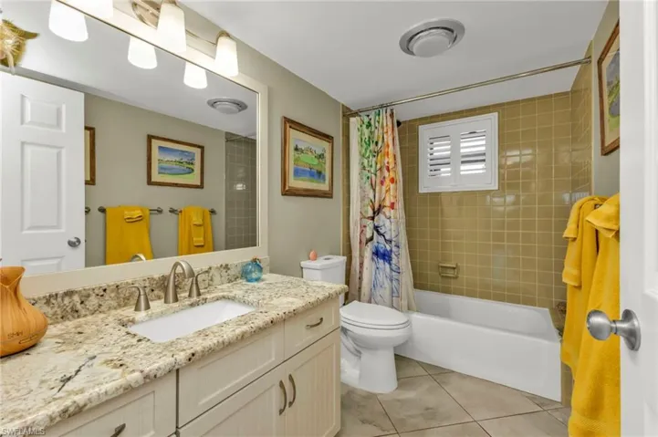 Bathroom featuring toilet, shower / tub combo, tile patterned flooring, and vanity