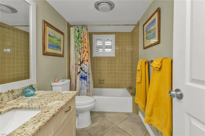 Bathroom featuring toilet, shower / bath combo, vanity, and tile patterned floors