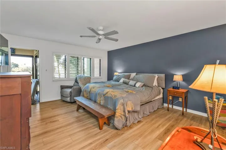 Bedroom with an accent wall, light wood-style flooring, baseboards, and a ceiling fan