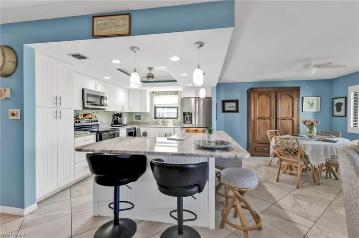 Kitchen featuring appliances with stainless steel finishes, a center island, a ceiling fan, and white cabinets