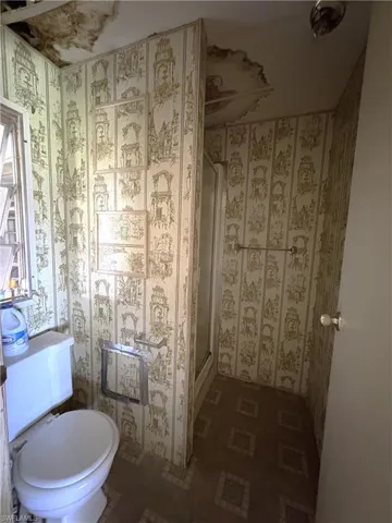 Bathroom featuring wallpapered walls and a stall shower