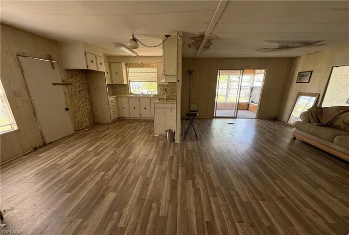 Unfurnished living room featuring dark wood-style flooring and wood walls