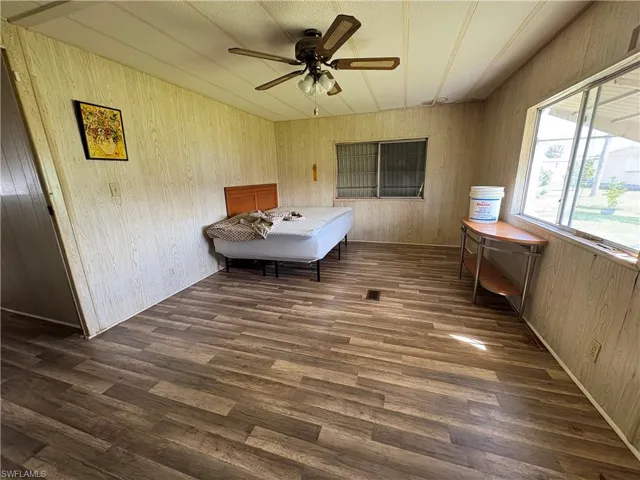 Bedroom with wooden walls, dark wood-style flooring, and ceiling fan