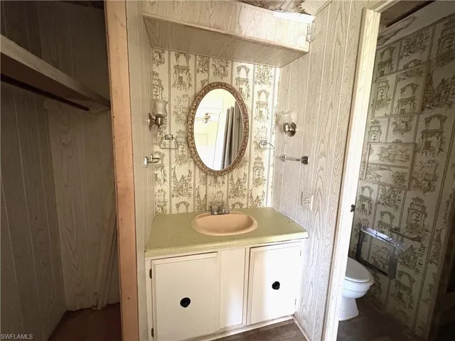 Bathroom featuring wallpapered walls and vanity