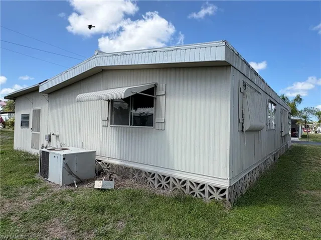 View of side of home featuring a central air condition unit and a lawn