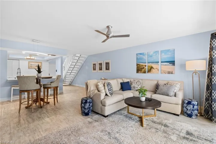 Living area featuring ceiling fan, stairway, baseboards, and wood finished floors